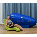 Woman seated next to Macy-Pan ST2200 Hyperbaric Oxygen Therapy Chamber, showcasing advanced recovery technology.