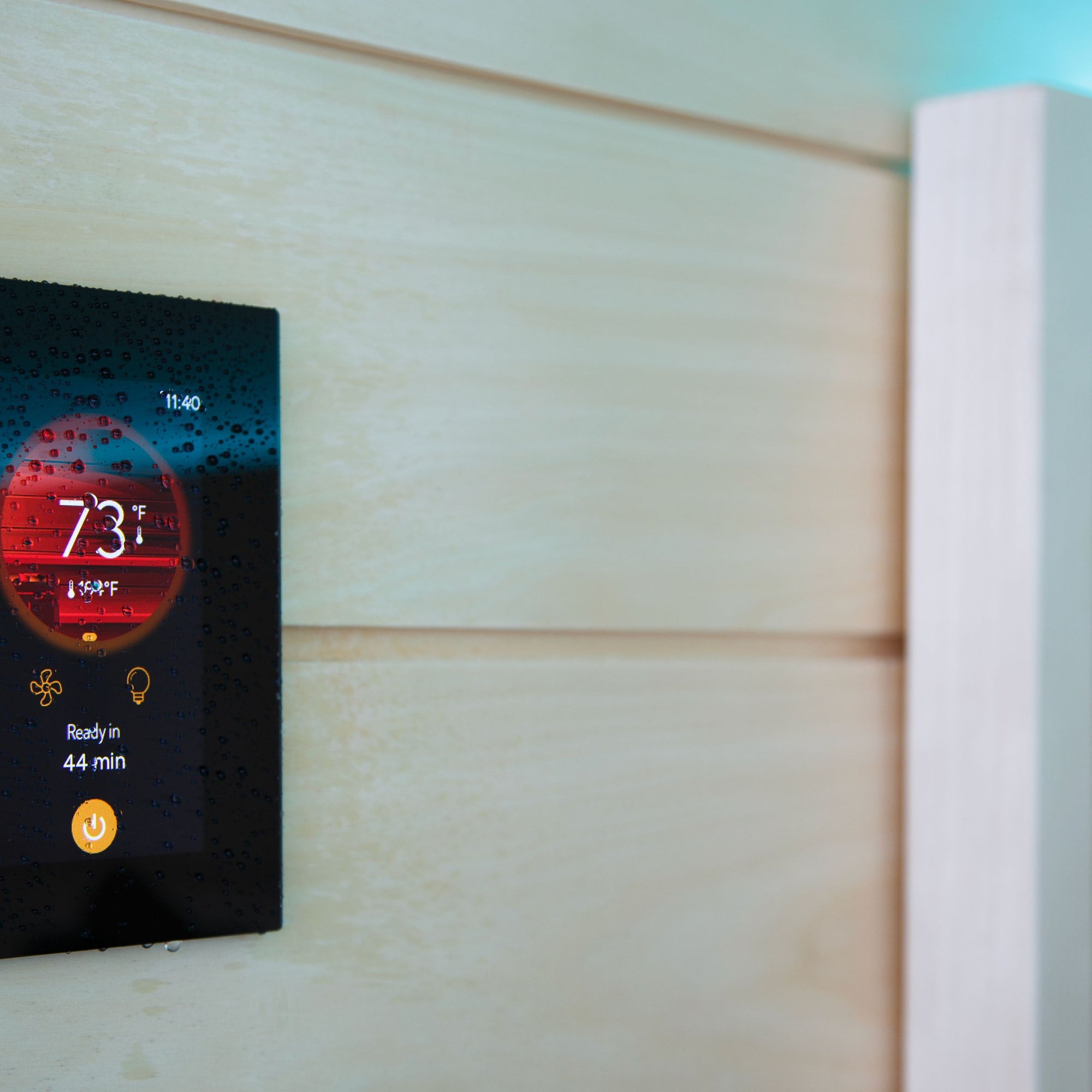 Harvia Fenix sauna control touchscreen mounted on a light wood sauna wall