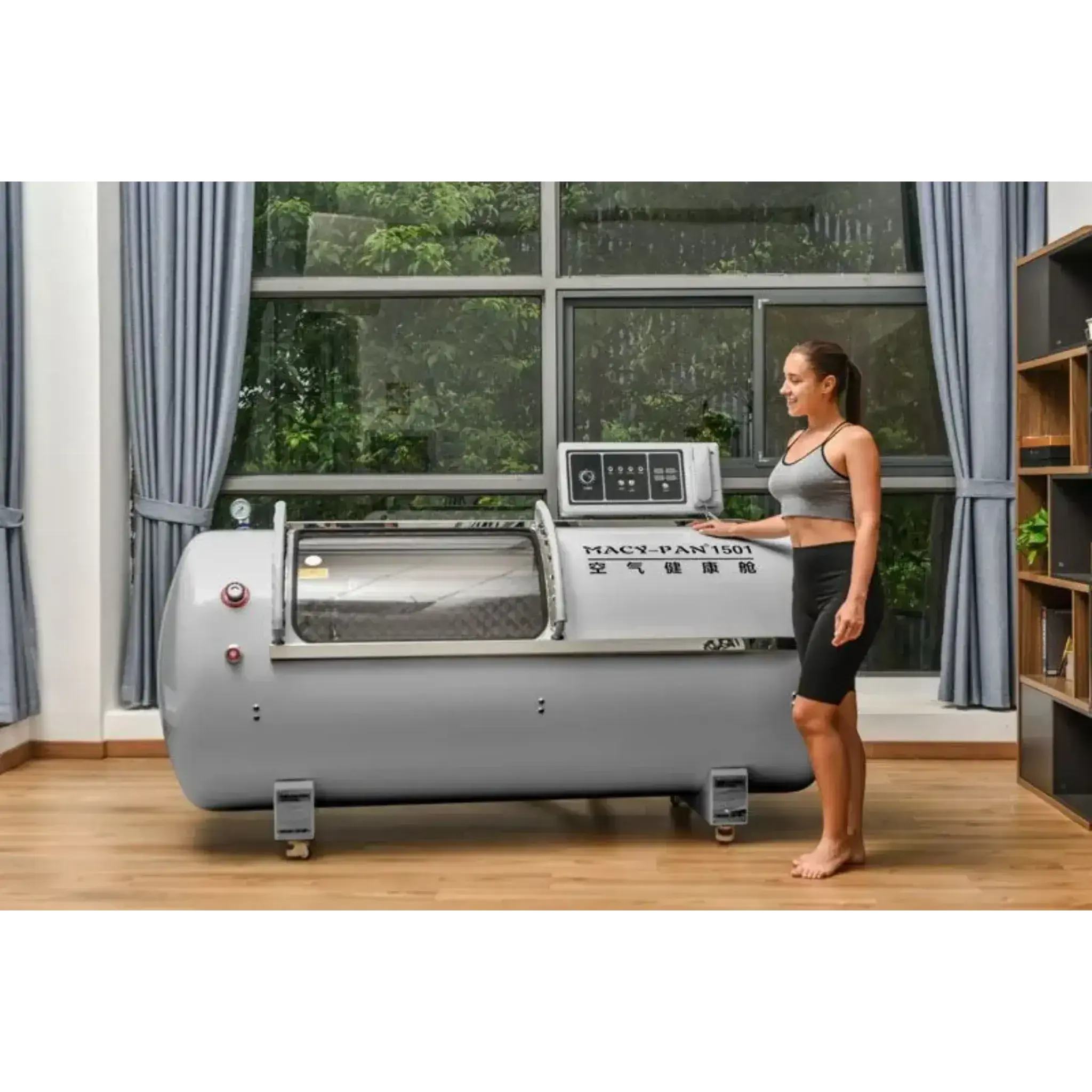 Woman standing next to Macy-Pan HP1501 hyperbaric oxygen therapy chamber in a modern room.