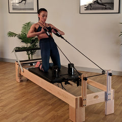 Align Pilates M8-Pro maple reformer with Half Cadillac, instructor on the carriage working the ropes