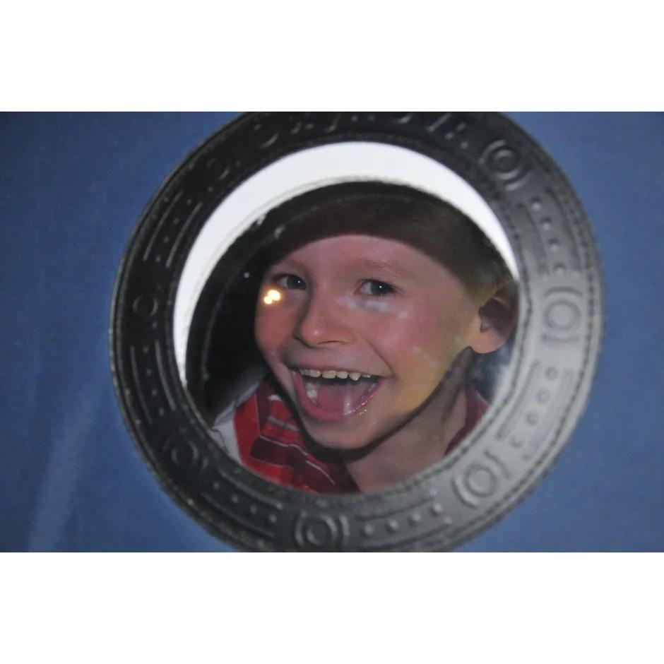 Child smiling through the window of an oxynova 7 soft‑shell hbot chamber