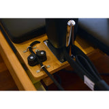 Close-up of the Basi Pilates reformer detailing the metal handle and pulley system on the wooden frame.