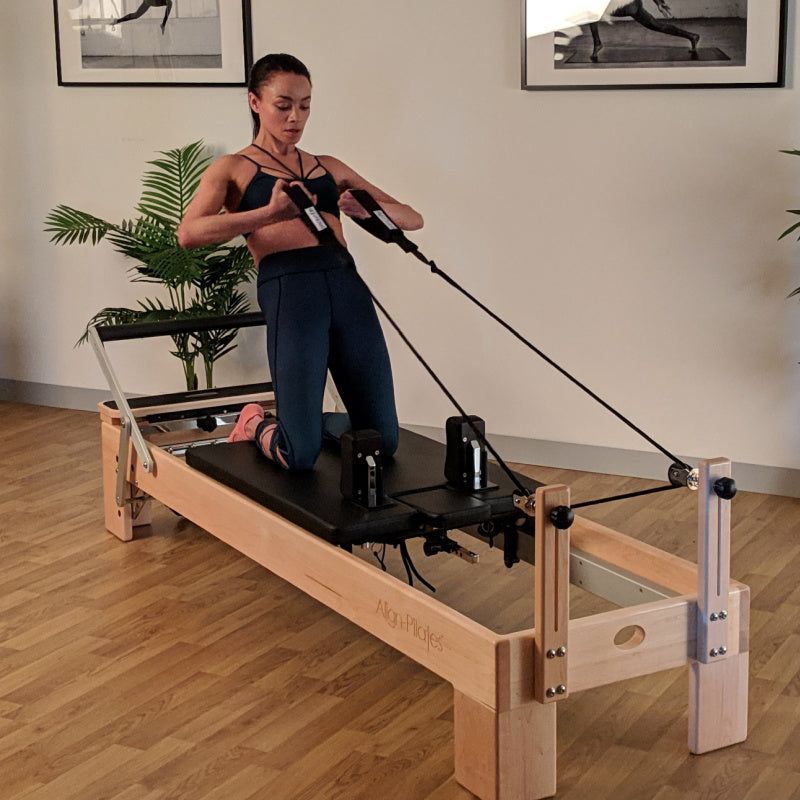 Align Pilates M8-Pro maple reformer with Half Cadillac, instructor on the carriage working the ropes
