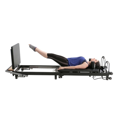 Instructor demonstrating a pilates exercise on the Align Pilates F2, showcasing the machine's stability and versatility.