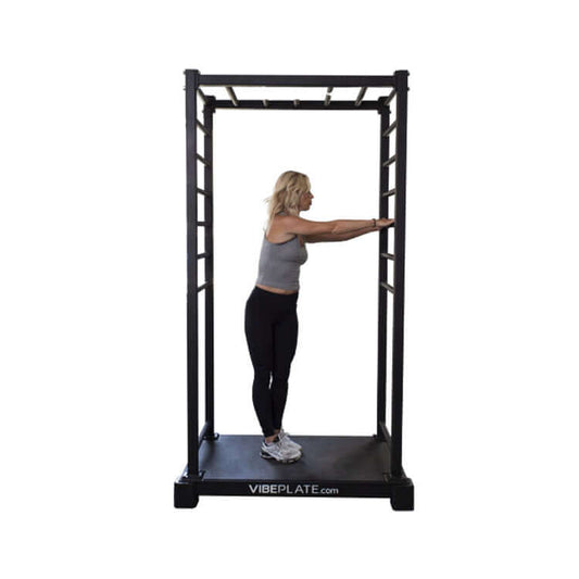Woman performing a forward arm stretch on the VibePlate VibeStretch vibration platform, engaging in flexibility training